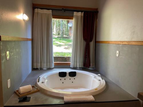 a large bath tub in a room with a window at Hotel Cabanas Glamour in Gramado