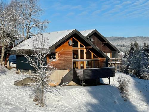 a log cabin in the snow with a bench in front at Chalet 22 Bernau in Bernau im Schwarzwald
