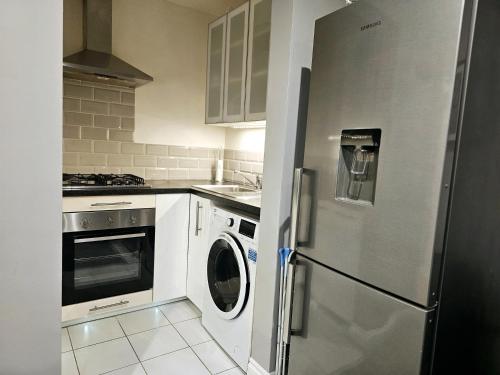 a kitchen with a refrigerator and a washer and dryer at Stay Zen Apartments - Free Parking & Private Garden Ground Floor Central Woking - Business & Leisure in Woking