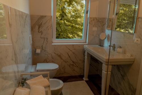 a bathroom with a sink and a toilet and a window at Locanda Gaudemus Boutique Hotel in Sistiana
