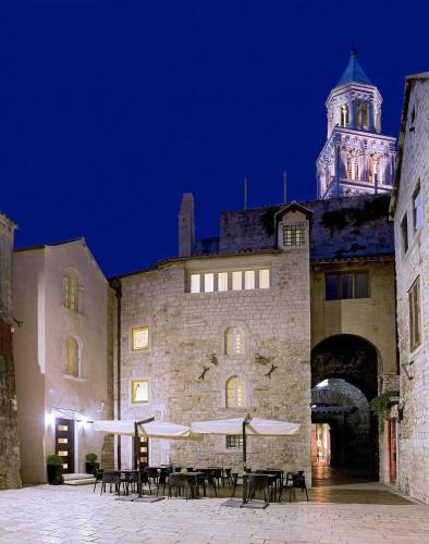 a building with tables and umbrellas in front of it at Hotel Vestibul Palace & Villa - Small Luxury Hotels Of The World in Split