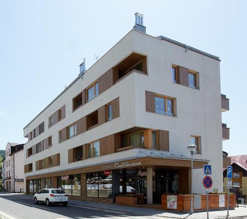 a white car parked in front of a building at Apartment Rezidence - Javor & Wellness in Železná Ruda
