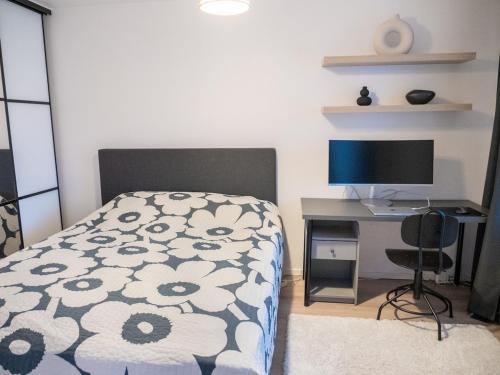 a bedroom with a bed and a desk with a computer at Two-room flat with sauna, glazed balcony and free parking lot in Helsinki