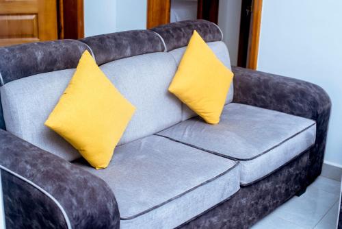 a gray couch with two yellow pillows on it at Martin Aviator Apartment in Kigali