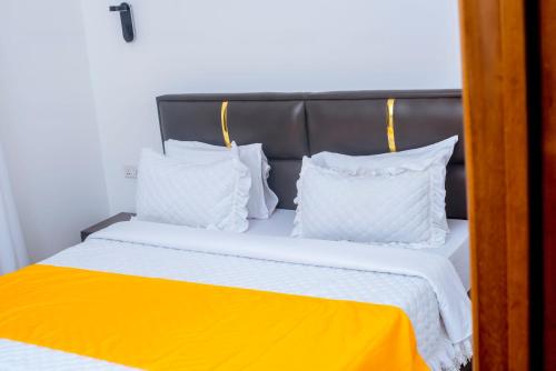 a bed with white pillows and a black head board at Martin Aviator Apartment in Kigali