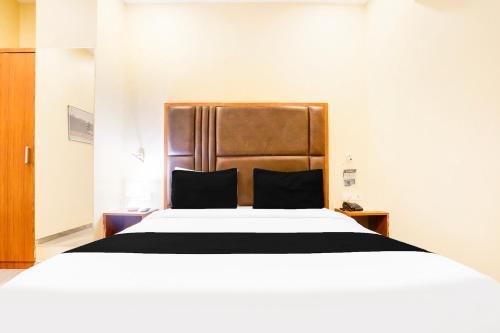 a bedroom with a large bed with a wooden headboard at Townhouse Talwandi formerly Paras Royale in Kota
