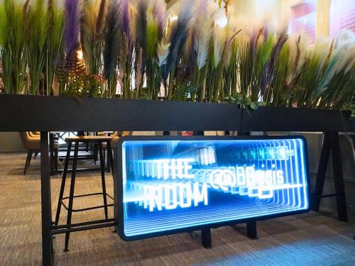 a sign that is sitting in front of some plants at The Room @ Bugis in Singapore