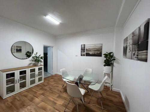a dining room with a glass table and white chairs at Como Beach Apartments in Perth
