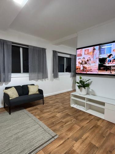 a living room with a couch and a flat screen tv at Como Beach Apartments in Perth