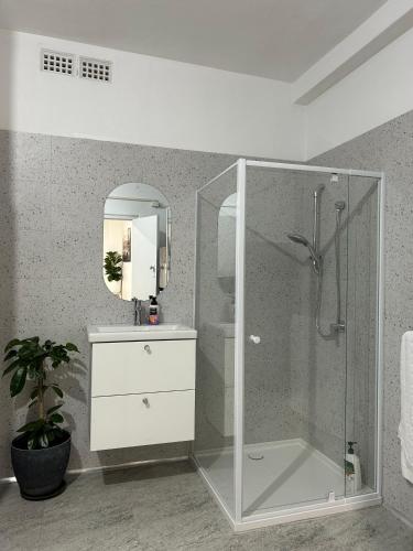a bathroom with a glass shower and a sink at Como Beach Apartments in Perth