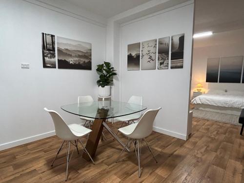 a dining room with a glass table and white chairs at Como Beach Apartments in Perth