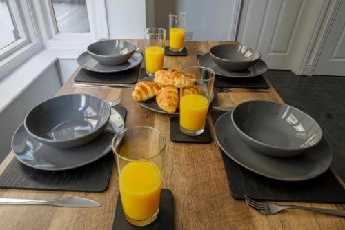 a table with plates of food and glasses of orange juice at Coastal 3-Bed with Great Rates for Long Stays in Cleethorpes