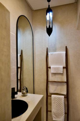 a bathroom with a sink and a mirror and towels at Riad Solange in Marrakesh