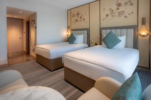 a hotel room with two beds and a couch at Signia by Hilton in Amman