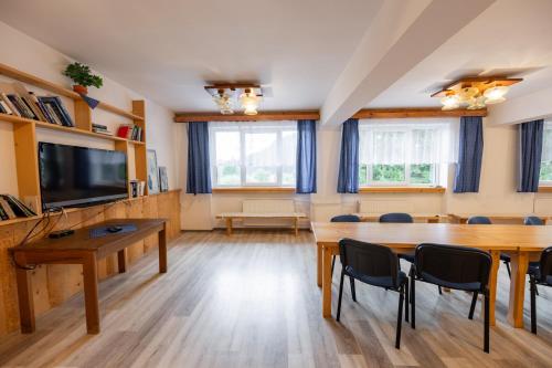a living room with a table and chairs and a tv at Horský hotel Kyčerka in Velké Karlovice