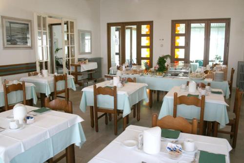 un restaurante con mesas y sillas con mesas blancas en Hotel Bermuda, en Marina di Ravenna