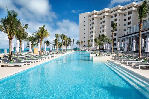 a swimming pool with chairs and palm trees and a building at Melia Casa Maya Cancun All Inclusive in Cancún