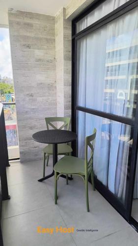 a table and chairs in a room with a window at Flats Tramonto - By EasyHost in João Pessoa