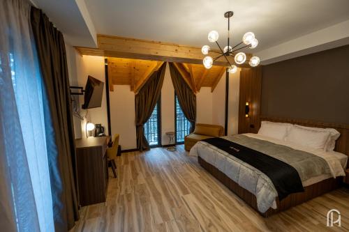 a bedroom with a large bed and a chandelier at PineHill Hotel, Restaurant , Pool & Spa - RAZEM in Razëm