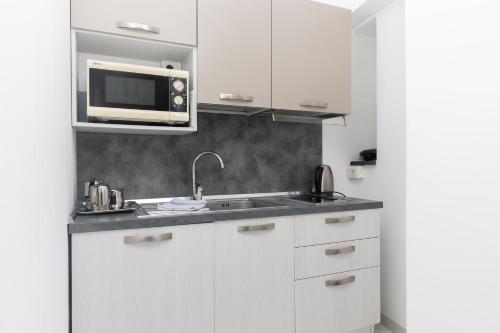 a white kitchen with a sink and a microwave at Coltur Suites in Sorrento