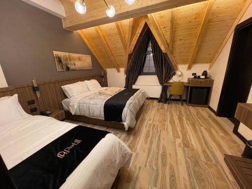 two beds in a room with a wooden ceiling at PineHill Hotel, Restaurant , Pool & Spa - RAZEM in Razëm