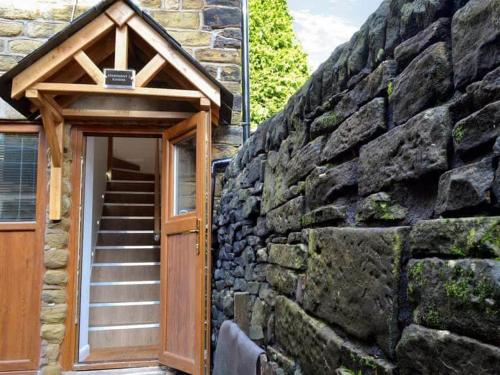 a stone building with a wooden door and a stone wall at Kinder Apartment Central Glossop in Glossop