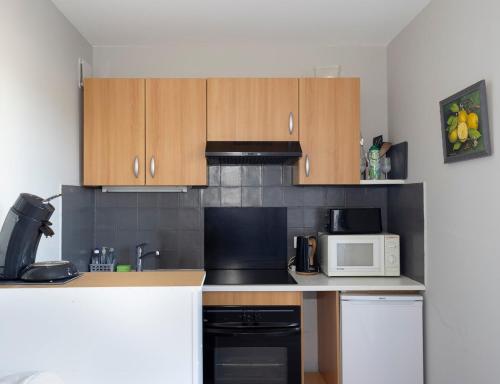 - une cuisine avec des placards en bois et un four micro-ondes blanc dans l'établissement Agréable Studio Port Leucate, à Leucate-Plage