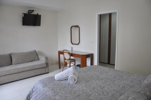 a bedroom with a bed and a couch and a table at Champagnat Praia Hotel in Vila Velha