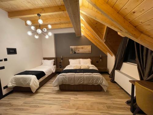 two beds in a room with wooden ceilings at PineHill Hotel, Restaurant , Pool & Spa - RAZEM in Razëm