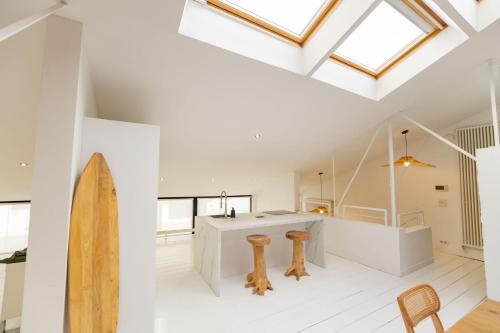 - une cuisine blanche avec une planche de surf dans une pièce dotée de lucarnes dans l'établissement Loft à Lorient, à Lorient