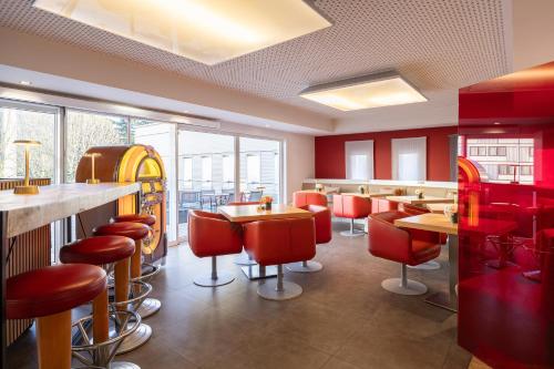 a restaurant with red chairs and tables and windows at Novotel Brussels Airport in Diegem