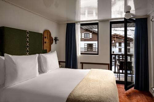 a bedroom with a white bed and a large window at Experimental Chalet Val d'Isère in Val dʼIsère