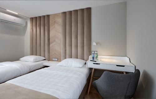 two beds in a room with a desk and a chair at Hotel Maria in Dębno Polskie