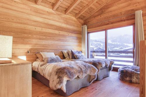 Cette chambre en bois dispose de 2 lits et d'une grande fenêtre. dans l'établissement Chalet La Petite Forêt, à Megève