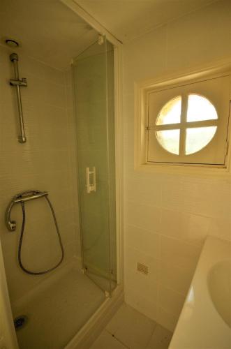 une salle de bain avec une douche avec une porte vitrée dans l'établissement Le Moulin du Moustoir VUE SUR LE GOLFE, à Locmariaquer