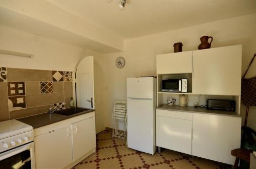 une cuisine avec des armoires blanches et un réfrigérateur blanc dans l'établissement Le Moulin du Moustoir VUE SUR LE GOLFE, à Locmariaquer