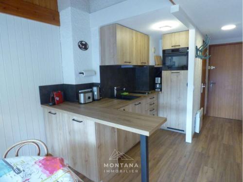 une cuisine avec des armoires en bois et un comptoir dans l'établissement T2 + coin nuit au pied des pistes, idéal pour 4 personnes - FR-1-458-187, au Grand-Bornand