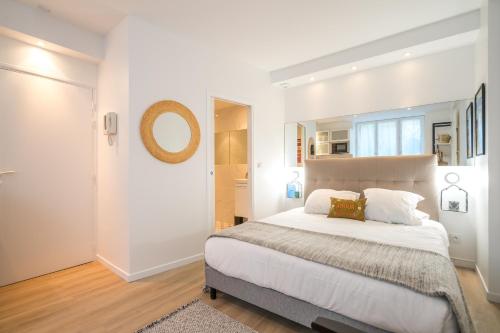 une chambre blanche avec un grand lit et un miroir dans l'établissement Happy Stay Paris - Cosy Studio 5 min to Eiffel Tower, à Paris