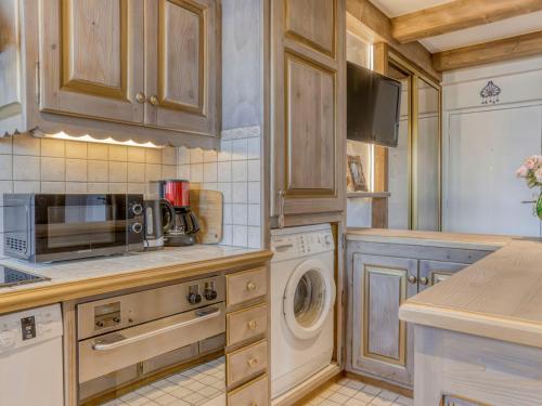 une cuisine avec des armoires en bois et une laveuse et une sécheuse dans l'établissement Appartement centre Megève - 2 pièces, Animaux admis, Wifi - FR-1-453-324, à Megève