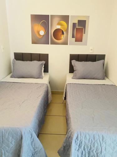 two beds in a room with paintings on the wall at Cerrado Gran Hotel in Rio Verde