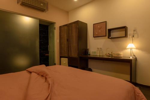 a bedroom with a bed and a desk with a lamp at Du De Homestay in Hoi An