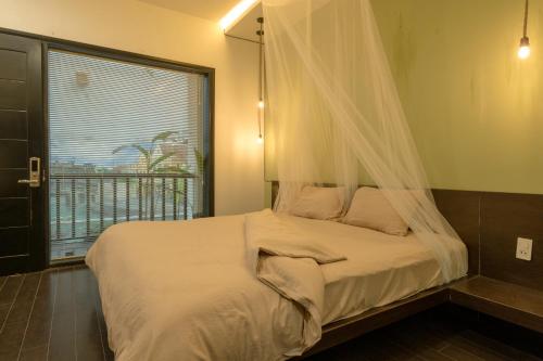 a bedroom with a bed with a mosquito net at Du De Homestay in Hoi An
