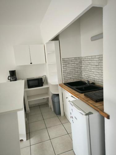 une petite cuisine avec des armoires blanches et un évier dans l'établissement Grande Rue Saint-Michel - Toulouse - CI - Cozy nest St Michel, à Toulouse