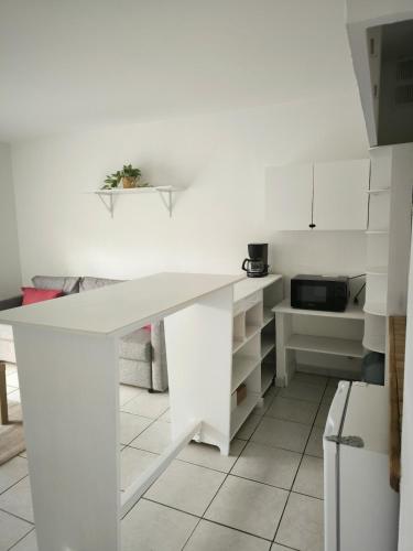 - une cuisine blanche avec un bureau blanc et un four micro-ondes dans l'établissement Grande Rue Saint-Michel - Toulouse - CI - Cozy nest St Michel, à Toulouse