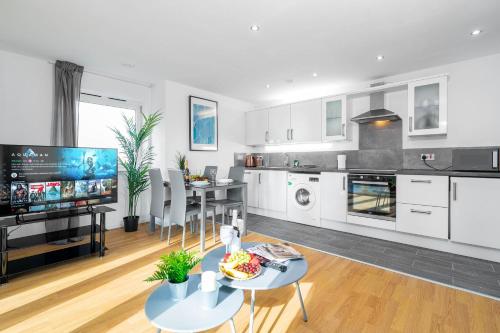 cocina con armarios blancos, mesa y TV en Stylish 2 Bedroom Apartment - City Centre - Large Balcony - Secure Parking 1001M, en Birmingham