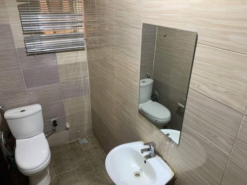 a bathroom with a sink and a toilet and a mirror at Hotel Fountain Blu in Abeokuta