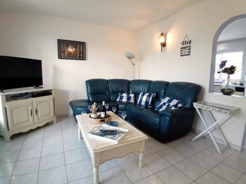 - un salon avec un canapé en cuir bleu et une table dans l'établissement Meschers sur Gironde - SEDUISANT COIN DE PARADIS avec sa PISCINE PRIVEE, à Meschers-sur-Gironde