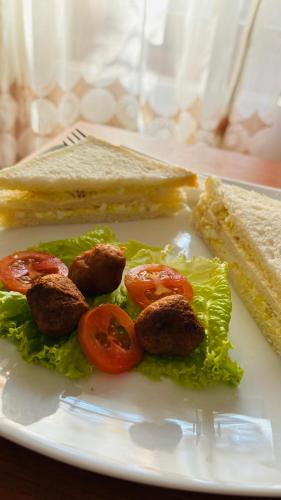 a white plate with a sandwich and tomatoes and lettuce at Mount Side Hiriketiya in Hiriketiya