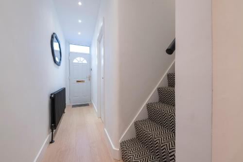 a hallway with stairs with a white door and a mirror at Cosy 4 bed with free parking, Chatham Town Centre in Chatham