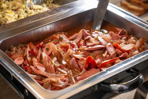 een pan met eten, ham en paprika's erin bij Hospedaje Arenas del Mar in Ilo